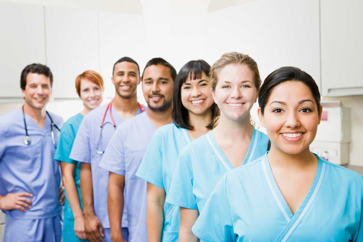 Group of nurses in a staggered line wearing blue scrubs