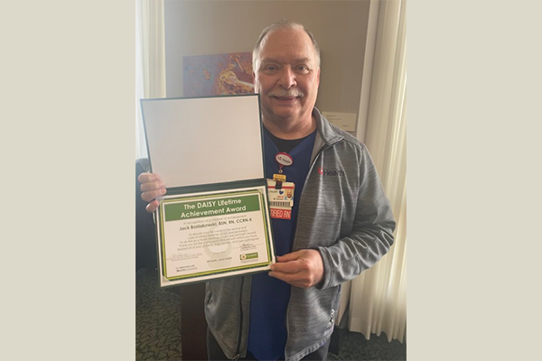 Jack Boniakowski smiles while holding his DAISY Lifetime Achievement Award, Winner Feb. 2022