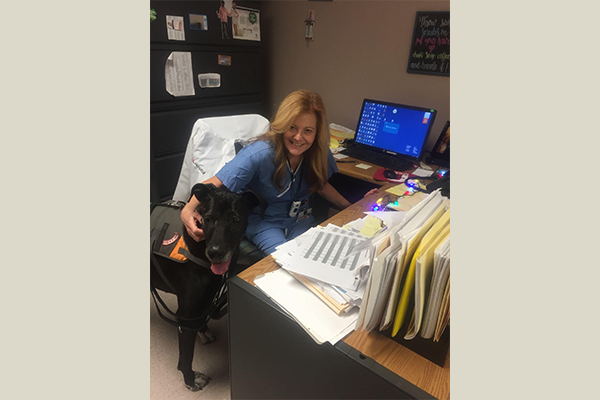 Photo of Kimberly Williams smiling while petting black dog