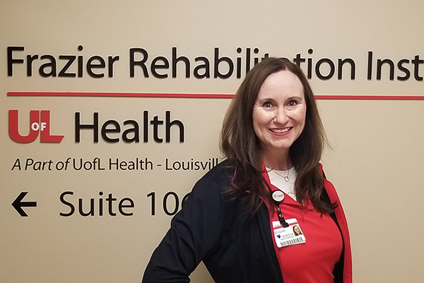 Photo of Rebecca McGuire in front of Frazier Rehab wall signage