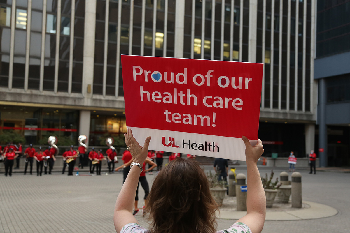 Woman holding UofL Health sign that reads, "Proud of our health care team!"